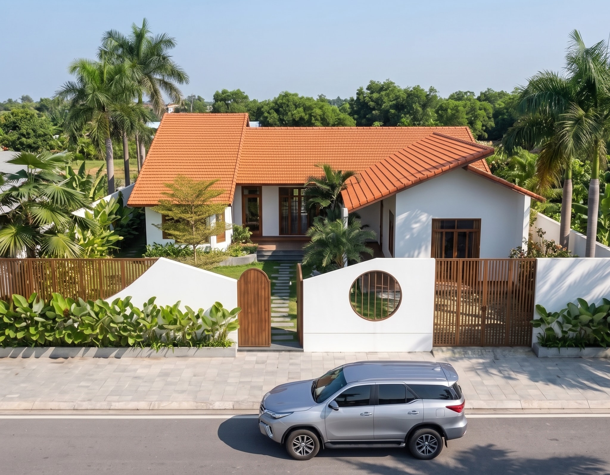 Mặt tiền Nam House nhìn từ đường với xe ô tô đậu trước cổng, mái ngói đỏ và sân vườn xung quanh