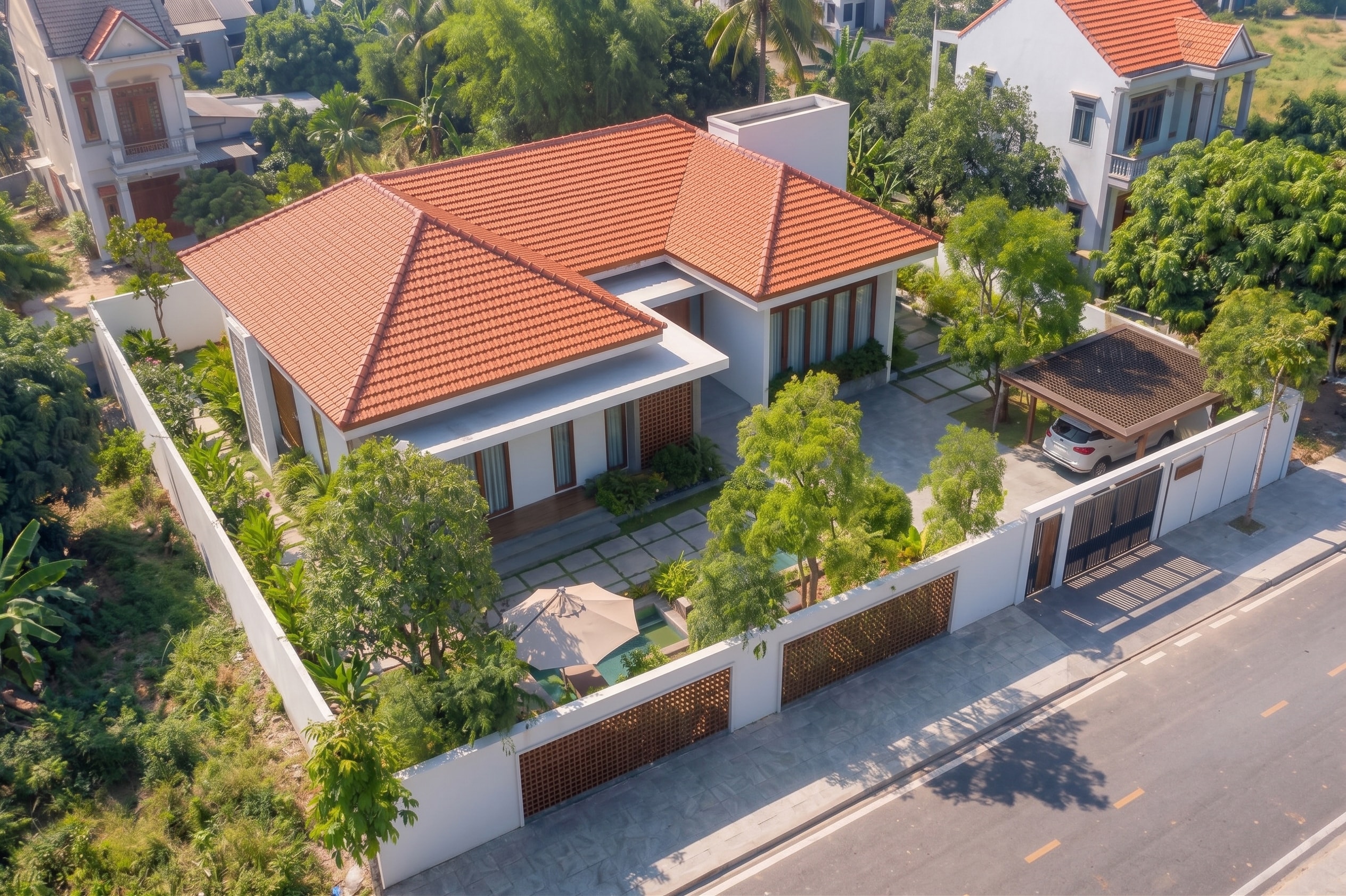 Góc nhìn từ trên cao mái ngói đỏ hình chóp của AJ House giữa khu dân cư nhiều cây xanh