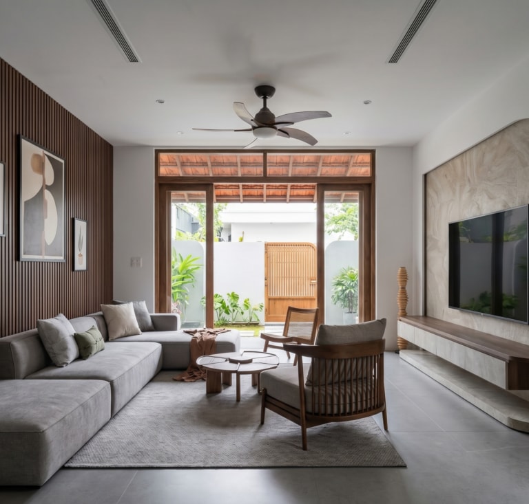 Phòng khách AJ House với vách gỗ nan, sofa và cửa kính nhìn ra sân vườn